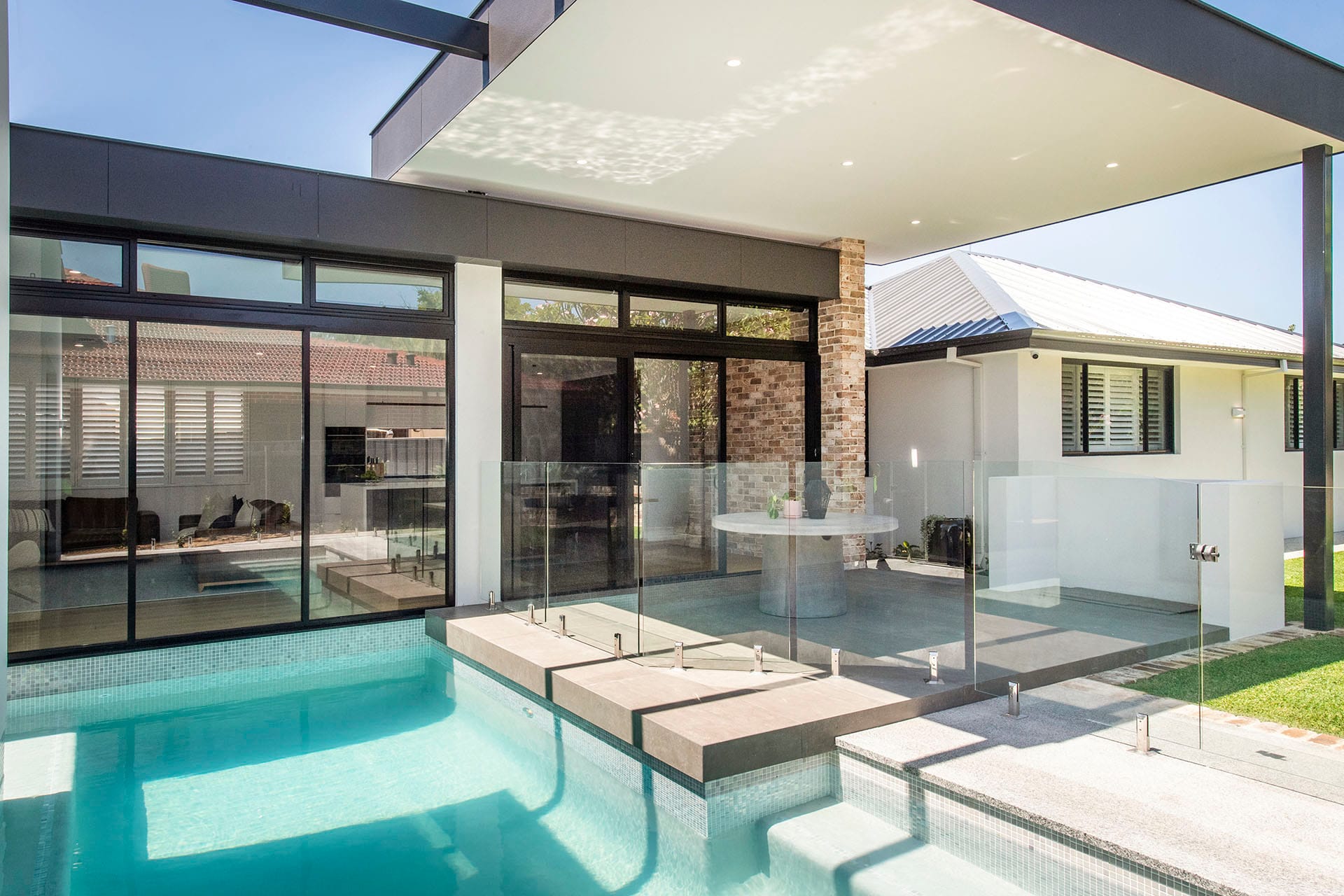 Glass-fenced pool integrated with a covered alfresco and open-plan living area in a D.A. Burke custom home
