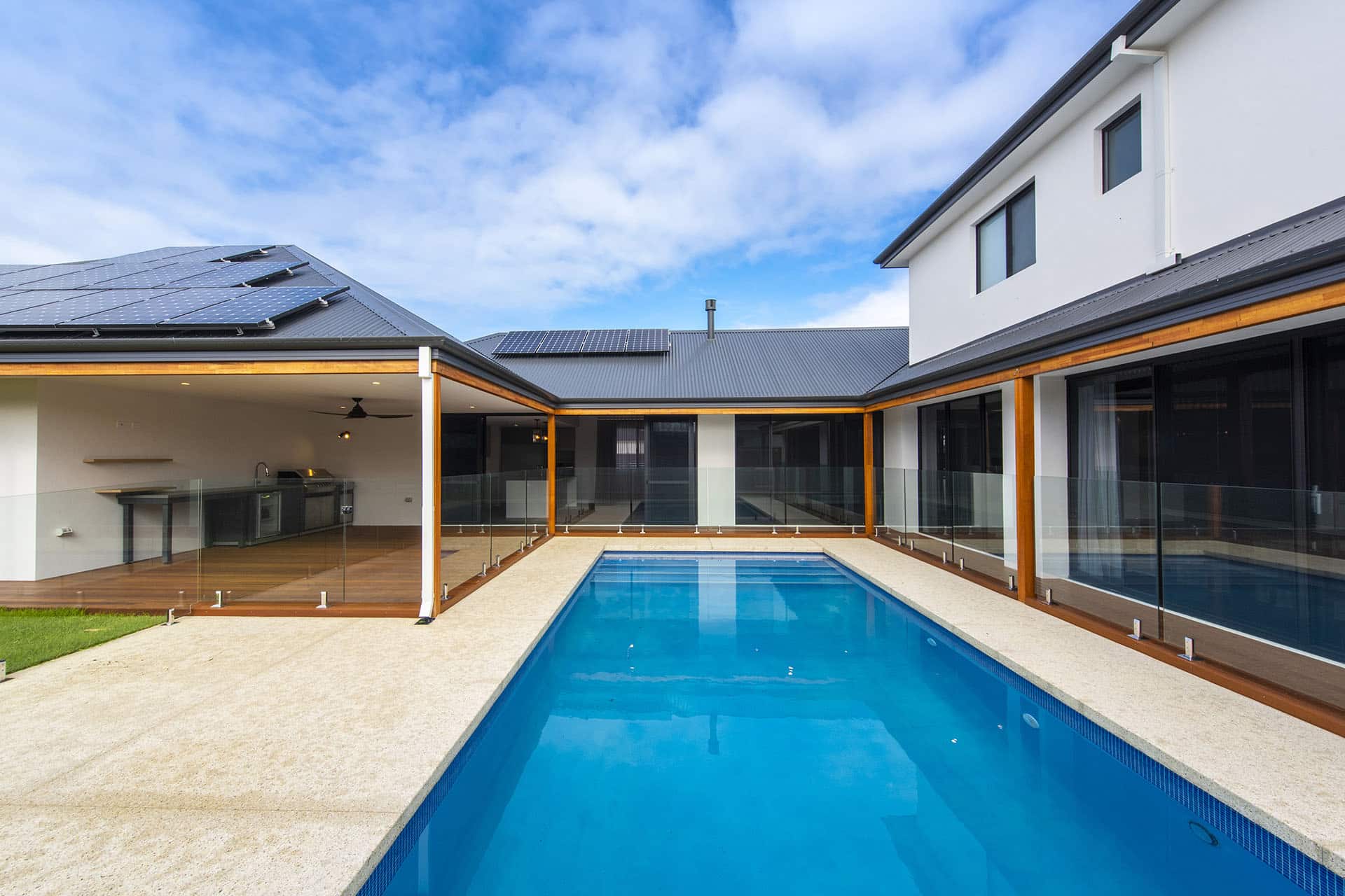 Infinity-edge pool, paved pool deck, and covered alfresco with outdoor kitchen at a D.A. Burke luxury home in Halls Head.