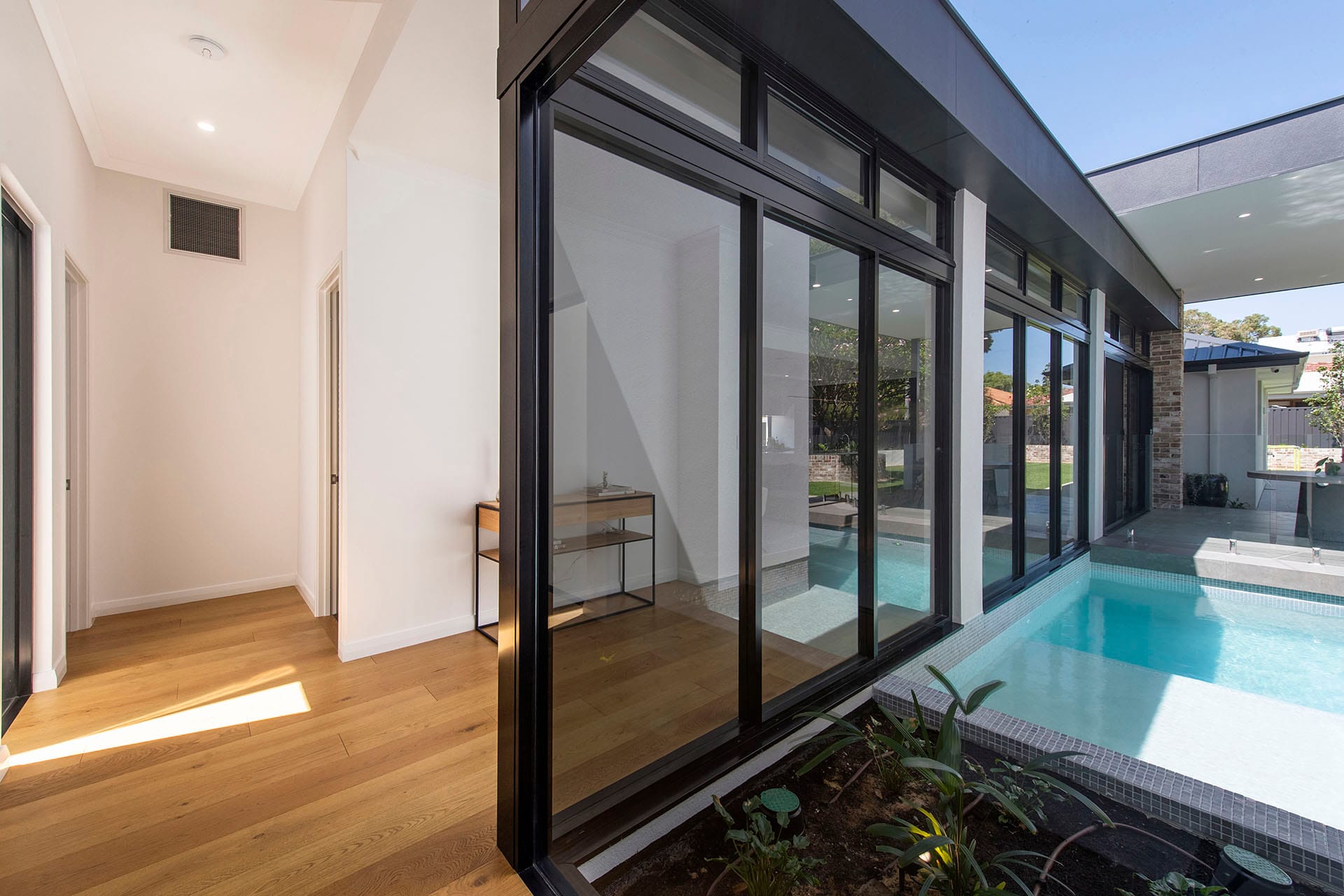 Plunge pool viewed from an open-plan living zone with floor-to-ceiling windows connecting indoor and outdoor spaces.