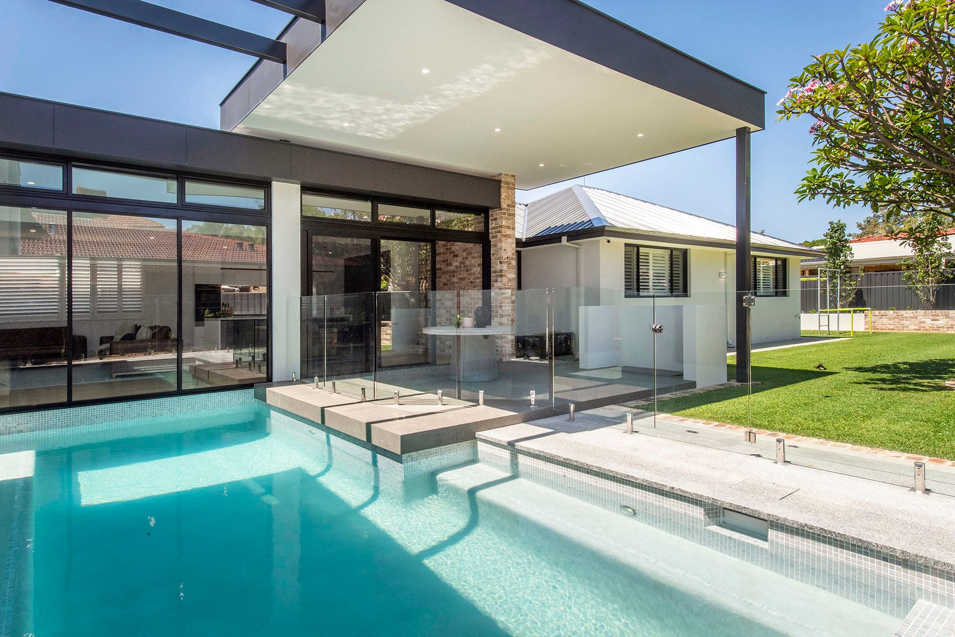 Glass-fenced plunge pool integrated with a covered alfresco and open-plan living area in a D.A. Burke custom home
